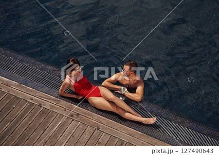 With cocktail. Man with woman is in the pool together 127490643