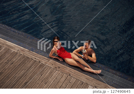 With cocktail. Man with woman is in the pool together 127490645