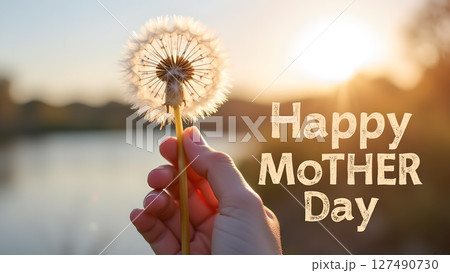 Gentle mother's day greeting: a dandelion held against a serene sunset backdrop 127490730