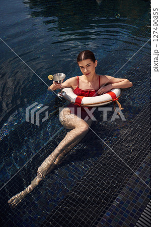 With drink in hand. Young woman in red swimsuit is in the pool 127490855