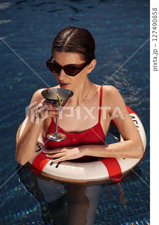 With lifebuoy. Young woman in red swimsuit is in the pool With lifebuoy. Young woman in red swimsuit is in the pool 127490858