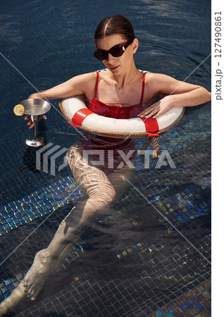 With lifebuoy. Young woman in red swimsuit is in the pool 127490861