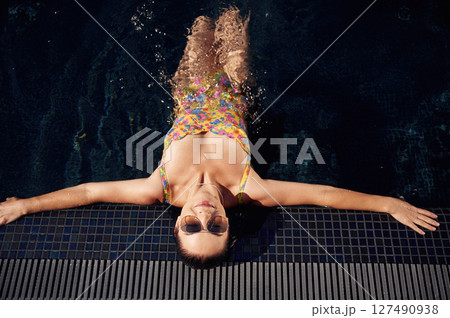 Top view. Beautiful woman that is in swimsuit is in the pool Top view. Beautiful woman that is in swimsuit is in the pool 127490938