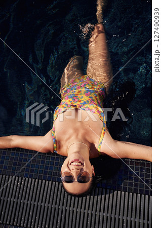 Top view. Beautiful woman that is in swimsuit is in the pool Top view. Beautiful woman that is in swimsuit is in the pool 127490939