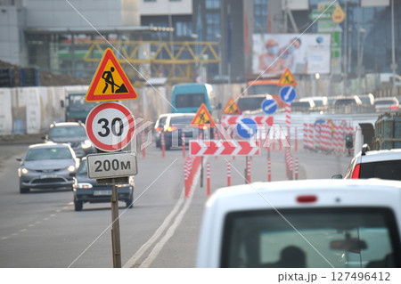 Roadworks warning traffic signs of construction work on city street and slowly moving cars 127496412