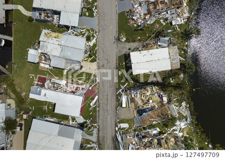 Hurricane destroyed suburban houses roofs in Florida mobile home residential area. Consequences of natural disaster 127497709