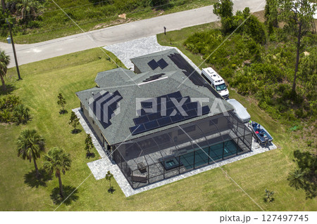 Home roof with blue solar photovoltaic panels for producing clean ecological electric energy. Investing in renewable electricity for retirement income Home roof with blue solar photovoltaic panels for producing clean ecological electric energy. Investing in renewable electricity for retirement income 127497745