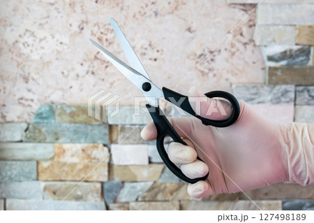 Scissors in the hand with rubber glove. Steel shears for cutting. 127498189