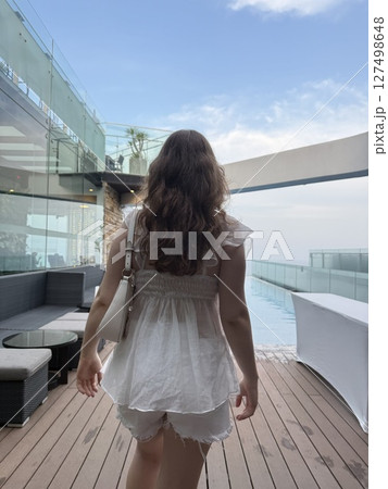 Vietnam Danan girl high floor city view sea vertical photos lounges on a rooftop resort hotel deck overlooking the ocean on a bright blue clear summer day 127498648
