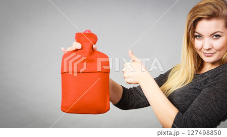 Happy woman holds hot water bottle Happy woman holds hot water bottle 127498850