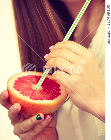 Woman holds grapefruit drinking juice from fruit 127499100