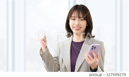 スマートフォンを持ってガッツポーズをする若い女性・ビジネスウーマン 127499279