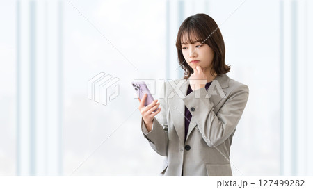 スマートフォンを見て考える女性・ビジネスウーマン 127499282