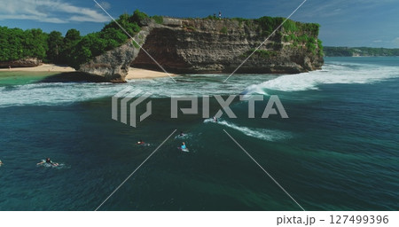 Aerial drone footage of surfers waiting for the perfect wave at the famous Pantai Dreamland Beach, Bali, Indonesia, showcasing the beautiful coastline and lush vegetation 127499396