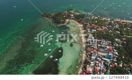 Stunning aerial view of Malapascua Island in the Philippines, featuring traditional outrigger boats on turquoise waters, a pristine beach, lush greenery, and colorful village houses Stunning aerial view of Malapascua Island in the Philippines, featuring traditional outrigger boats on turquoise waters, a pristine beach, lush greenery, and colorful village houses 127499410
