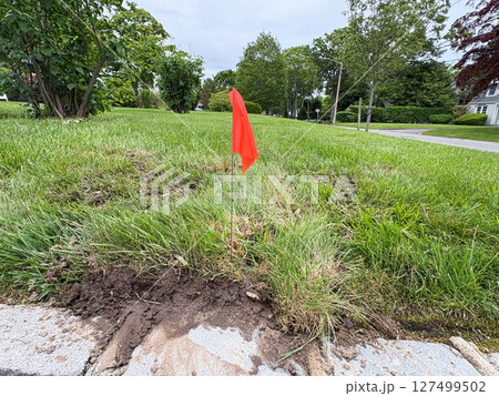 Bright Red Flag Marks Landscaping Work on a Grassy Area Near a Road Bright Red Flag Marks Landscaping Work on a Grassy Area Near a Road 127499502