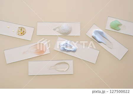 Textures of cosmetic products in a chaotic manner on a beige background. Textures of cosmetic products in a chaotic manner on a beige background. 127500022