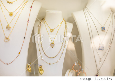 Layered necklaces with heart pendants on display. Romantic jewelry, elegant design, and retail charm. 127500175