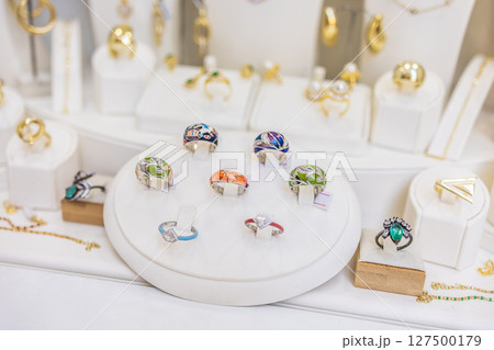 Colorful designer rings in elegant showcase. Fashion expression, modern jewelry, and artistic accessory style. 127500179