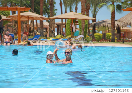 Mother catching her daughter jumping into swimming pool. Happy holidays Mother catching her daughter jumping into swimming pool. Happy holidays 127501148