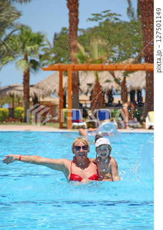 Mother catching her daughter jumping into swimming pool. Happy holidays 127501149