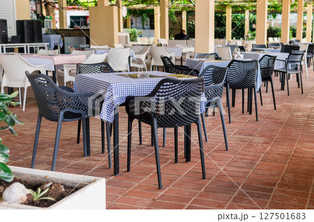 Modern restaurant terrace with set tables and chairs. Casual dining, cozy atmosphere, and summer hospitality experience. Modern restaurant terrace with set tables and chairs. Casual dining, cozy atmosphere, and summer hospitality experience. 127501683