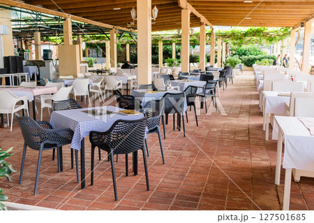 Modern restaurant terrace with set tables and chairs. Casual dining, cozy atmosphere, and summer hospitality experience. 127501685