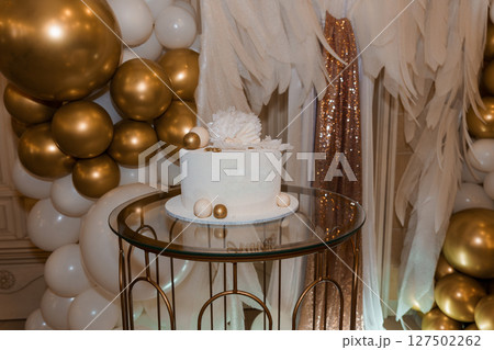 Elegant White Cake with Gold Accents for Birthday Celebration Backdrop with Balloons and Feathers Elegant White Cake with Gold Accents for Birthday Celebration Backdrop with Balloons and Feathers 127502262