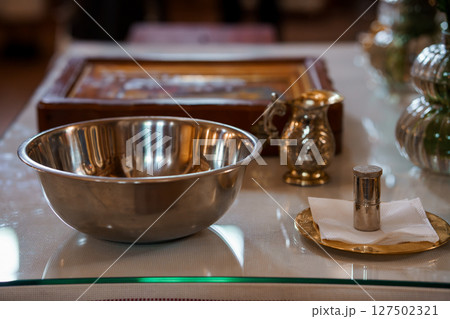 Christian Baptism Preparation Table Scene: Silver Bowl, Pitcher, Candle, Cross and Bible, Spiritual Ritual, Soft Lighting, Religious Ceremony 127502321
