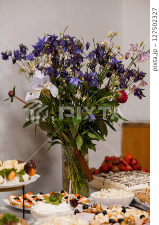 Beautiful Banquet Table Setting with Blue Flowers, Desserts and Fresh Fruit: Elegant Food Display with Lilies and Festive Treats 127502327