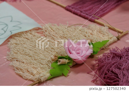 Handmade Flower Craft Project: Jute Weaving with Pink Rose Decoration on Pale Pink Backdrop, DIY Art Texture 127502340