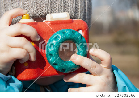 Little photographer with toy camera. Child playing outdoors 127502366