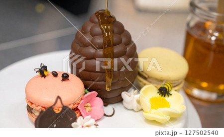 Chocolate covered beehive dripping honey onto macaron flowers. Generated Image Chocolate covered beehive dripping honey onto macaron flowers. Generated Image 127502540