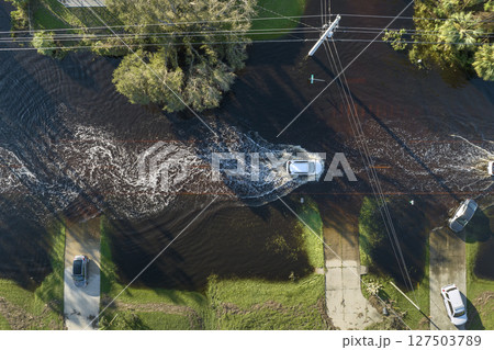 Flooded Florida road with evacuating cars and surrounded with water houses in suburban residential area. Consequences of hurricane natural disaster Flooded Florida road with evacuating cars and surrounded with water houses in suburban residential area. Consequences of hurricane natural disaster 127503789
