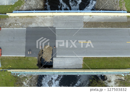 Destroyed bridge after hurricane flooding in Florida. Construction roadwork site. Reconstruction of damaged road after flood water washed away asphalt 127503832