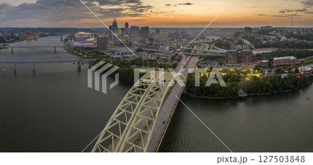 Daniel Carter Bridge in Cincinnati city, Ohio, USA with highway traffic driving cars in downtown district. American city skyline with brightly illuminated high commercial buildings at night Daniel Carter Bridge in Cincinnati city, Ohio, USA with highway traffic driving cars in downtown district. American city skyline with brightly illuminated high commercial buildings at night 127503848