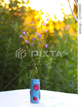 Purple campanula flowers in a vase with handmade paper details. 127504085