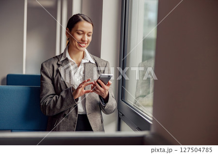 A businesswoman is skillfully utilizing her smartphone while in a contemporary office setting A businesswoman is skillfully utilizing her smartphone while in a contemporary office setting 127504785