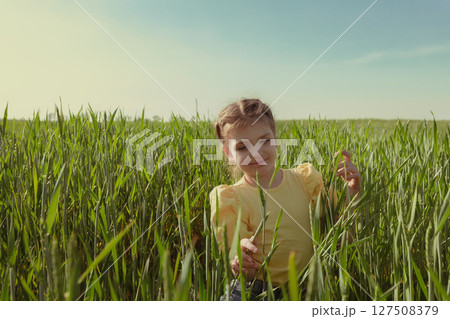 Portrait of happy 7-year-old girl stands on green rye field 127508379