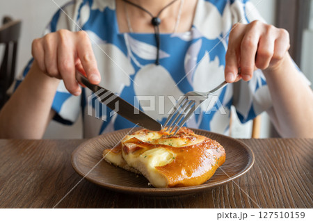 Cropped shot view of someone cutting a slice of cheese pretzel bun for eat. Cropped shot view of someone cutting a slice of cheese pretzel bun for eat. 127510159