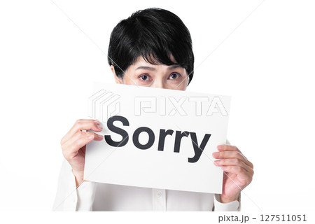 Sorryと書かれた紙を持つ上目遣いな中年女性 Sorryと書かれた紙を持つ上目遣いな中年女性 127511051