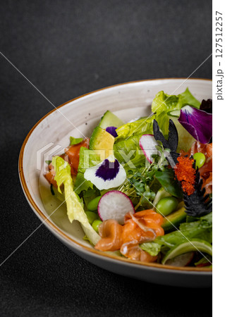 Mediterranean Avocado Salmon Salad with spinach, cherry tomatoes, avocado and red onion dressing. Concept for a tasty and healthy meal. Vegan food 127512257
