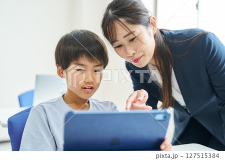 タブレット端末の操作を教わる小学生 127515384