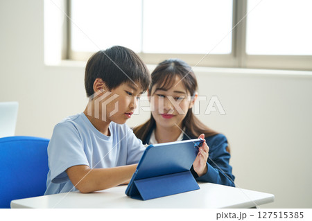 タブレット端末の操作を教わる小学生 127515385