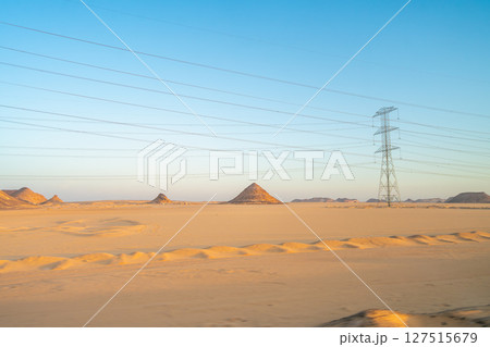 Power Lines Stretching Across the Desert Landscape at Sunrise in Aswan, Egypt. 127515679