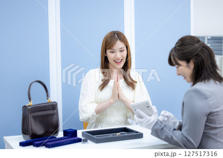 買取業者　バックと貴金属の査定を受ける女性 127517316