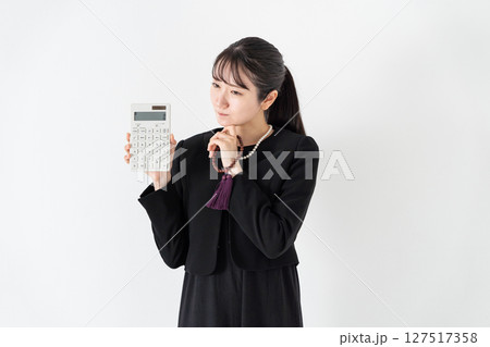 喪服の女性　計算機　悩む 127517358