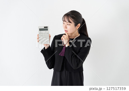 喪服の女性　計算機　悩む 127517359