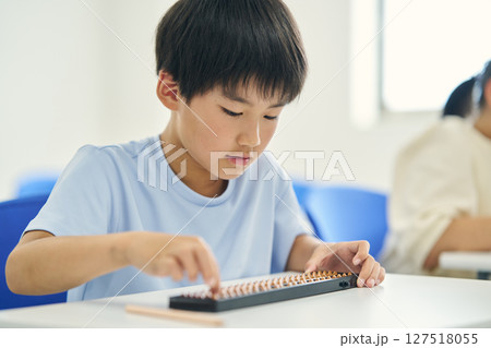 そろばんを教わる小学生 127518055
