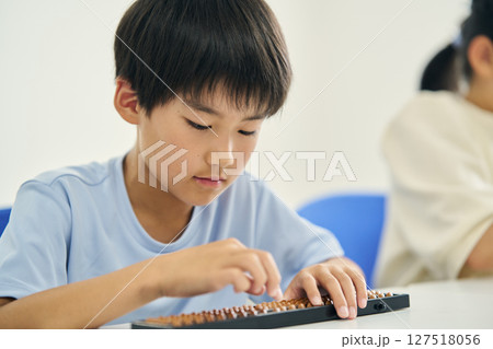 そろばんを教わる小学生 127518056
